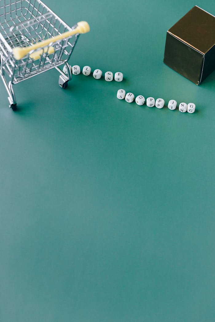 Close-up of a mini shopping cart with 'online shopping' spelled in letter blocks on a green background.