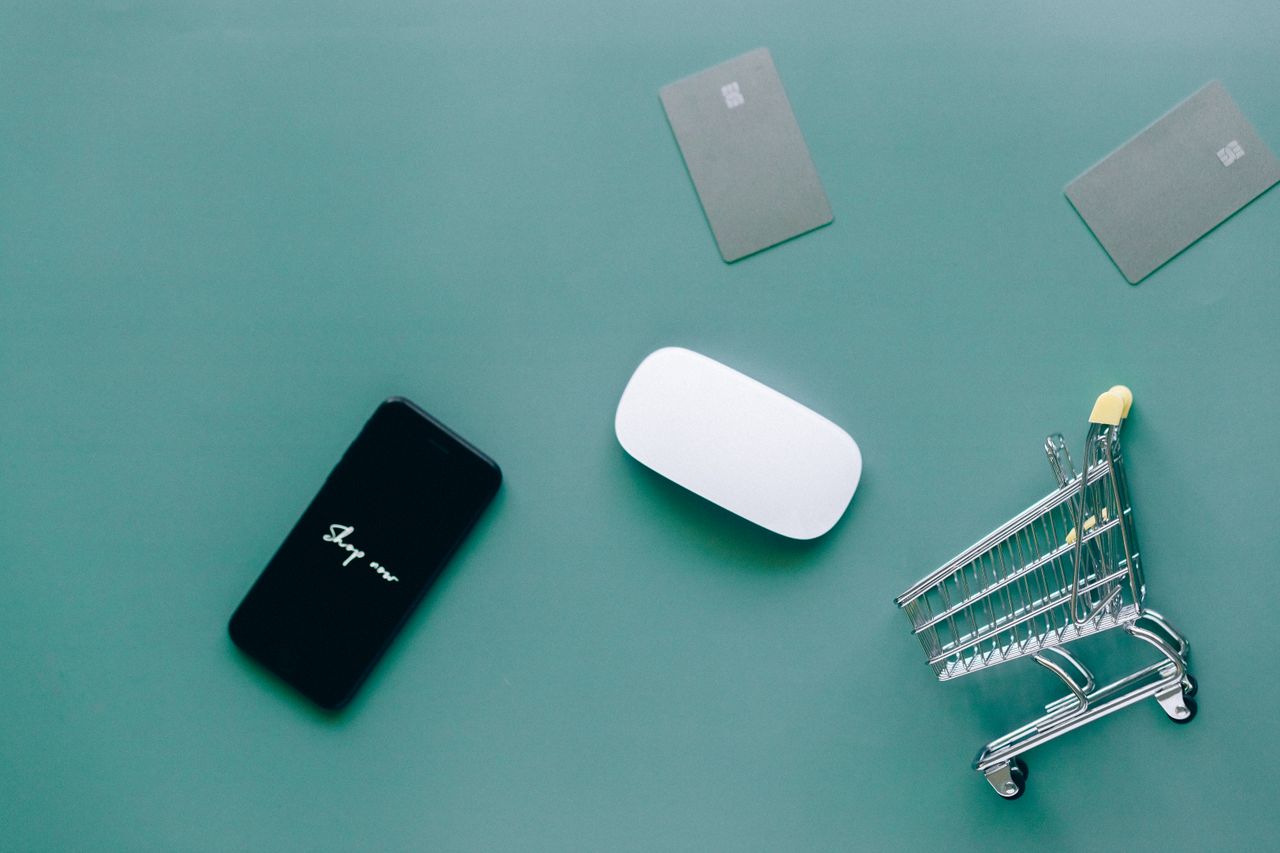 services-01 Flat lay of smartphone, cards, and shopping cart on green. Perfect for e-commerce and online shopping themes.